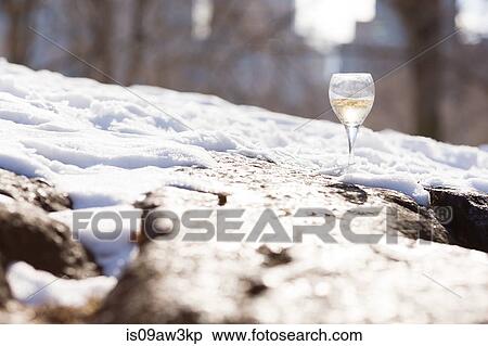Stock Photography - Surface level view of a glass of white wine in snow. Fotosearch