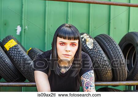 Tattooed woman in front of tyres looking at camera View Large Photo Image Stock Image - Tattooed woman in front of tyres looking at camera. Fotosearch