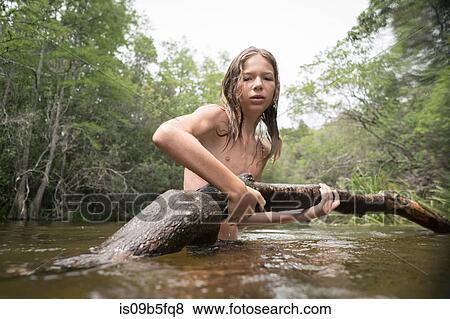 Teenage boy in lake holding tree branch View Large Photo Image Stock Photo - Teenage boy in lake holding tree branch. Fotosearch