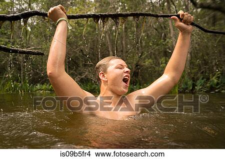 Teenage boy in water holding tree branch jubilantly, Turkey Creek, Niceville, Florida, USA View Large Photo Image Picture - Teenage boy in water holding tree branch jubilantly, Turkey Creek, Niceville, Florida, USA. Fotosearch