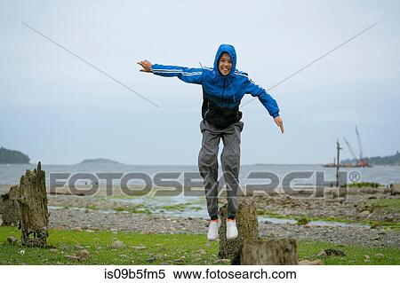 Stock Photography - Teenage boy jumping from tree stump, Pacific Rim National Park, Vancouver Island, Canada. Fotosearch