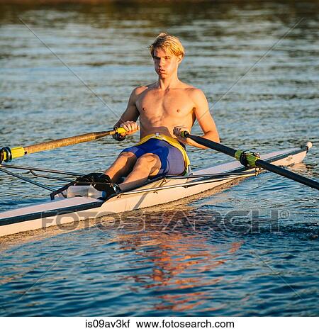 Stock Image - Teenage boy sculling on water. Fotosearch