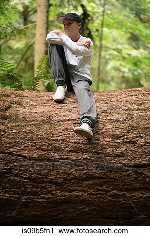 Teenage boy sitting on fallen tree trunk looking away, Pacific Rim National Park, Vancouver Island, Canada View Large Photo Image Stock Image - Teenage boy sitting on fallen tree trunk looking away, Pacific Rim National Park, Vancouver Island, Canada. Fotosearch