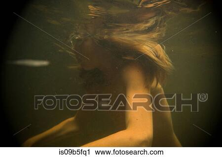 Stock Image - Teenage boy wearing swimming goggles underwater in lake. Fotosearch