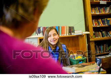 Stock Photo - Teenage girl in school speaking to guidance counselor smiling. Fotosearch