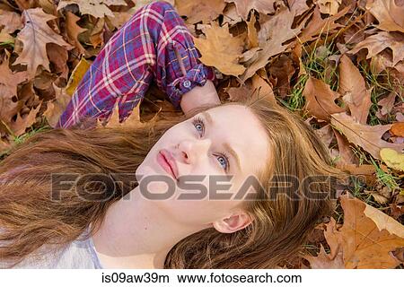 Picture - Teenage girl lying on autumn leaves, close-up. Fotosearch
