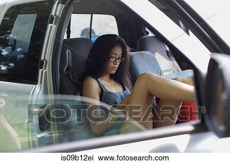 Teenage girl reading smartphone texts whist reclining in car with feet up View Large Photo Image Stock Image - Teenage girl reading smartphone texts whist reclining in car with feet up. Fotosearch