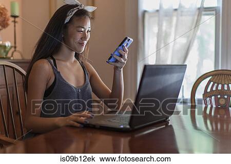 Teenage girl reading smartphone texts in dining room View Large Photo Image Stock Image - Teenage girl reading smartphone texts in dining room. Fotosearch
