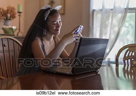 Teenage girl reading smartphone texts in dining room View Large Photo Image Stock Image - Teenage girl reading smartphone texts in dining room. Fotosearch