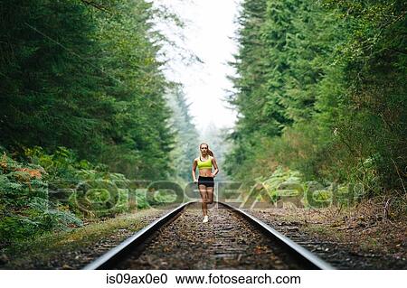 Teenage girl running along rural train track View Large Photo Image Stock Image - Teenage girl running along rural train track. Fotosearch