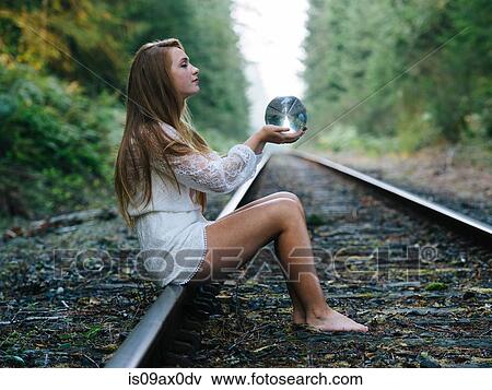 Teenage girl, sitting on train track, holding crystal ball View Large Photo Image Stock Photo - Teenage girl, sitting on train track, holding crystal ball. Fotosearch