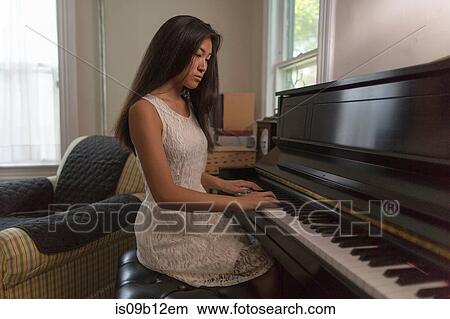 Teenage girl sitting playing piano in dining room View Large Photo Image Picture - Teenage girl sitting playing piano in dining room. Fotosearch
