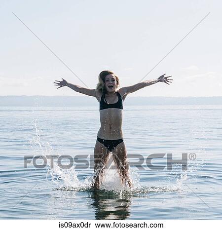 Teenage girl standing in sea, splashing water View Large Photo Image Stock Photography - Teenage girl standing in sea, splashing water. Fotosearch