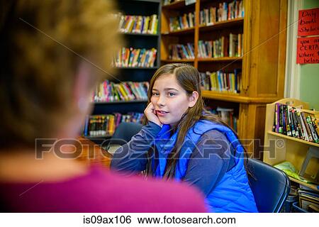 Teenage girl with hand on chin, in school library speaking to guidance counselor View Large Photo Image Stock Photograph - Teenage girl with hand on chin, in school library speaking to guidance counselor. Fotosearch