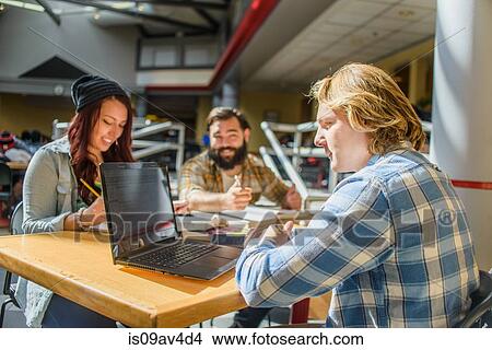 Three adult college students working at classroom desk View Large Photo Image Picture - Three adult college students working at classroom desk. Fotosearch