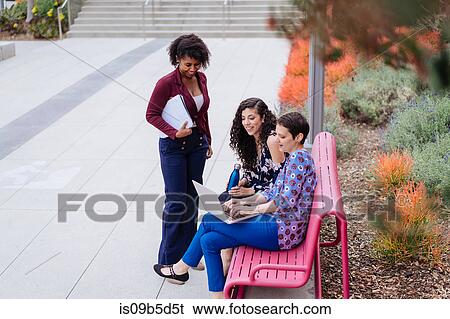 Three women outdoors, looking at laptop View Large Photo Image Stock Photograph - Three women outdoors, looking at laptop. Fotosearch