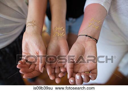 Three young women showing temporary 'Bride tribe' tattoos on wrists, close-up View Large Photo Image Stock Photograph - Three young women showing temporary 'Bride tribe' tattoos on wrists, close-up. Fotosearch