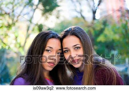Twin sisters smiling in park View Large Photo Image Stock Image - Twin sisters smiling in park. Fotosearch