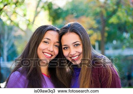 Twin sisters smiling in park View Large Photo Image Stock Image - Twin sisters smiling in park. Fotosearch