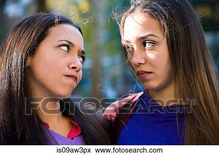 Twin sisters staring angrily at each other View Large Photo Image Stock Photo - Twin sisters staring angrily at each other. Fotosearch