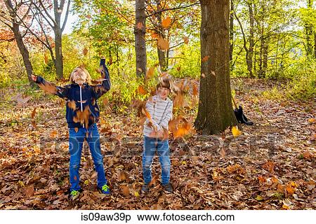 Stock Photography - Two brothers in forest, throwing autumn leaves. Fotosearch