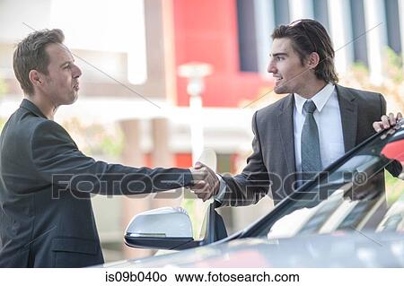 Two businessmen shaking hands in city View Large Photo Image Picture - Two businessmen shaking hands in city. Fotosearch