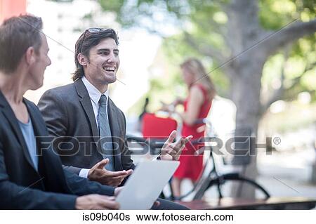 Two businessmen using laptop and chatting in city park View Large Photo Image Stock Photograph - Two businessmen using laptop and chatting in city park. Fotosearch