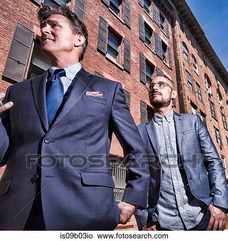 Two businessmen walking outdoors, low angle view View Large Photo Image Picture - Two businessmen walking outdoors, low angle view. Fotosearch