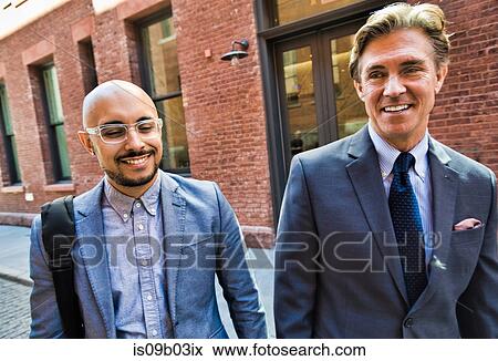 Two businessmen walking together in street, smiling View Large Photo Image Stock Photo - Two businessmen walking together in street, smiling. Fotosearch