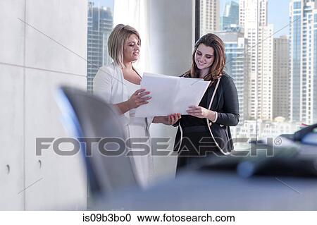 Two businesswomen reading paperwork at meeting in conference room View Large Photo Image Stock Image - Two businesswomen reading paperwork at meeting in conference room. Fotosearch