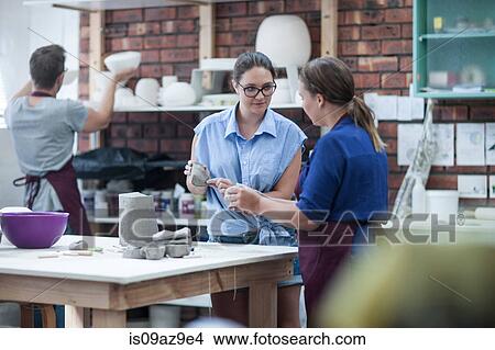 Picture - Two female potters shaping clay on workbench in workshop. Fotosearch