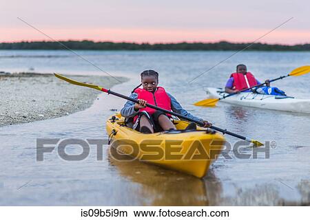 Two girls in canoes on water at sunset View Large Photo Image Picture - Two girls in canoes on water at sunset. Fotosearch