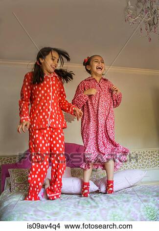 Two happy sisters jumping on bed View Large Photo Image Picture - Two happy sisters jumping on bed. Fotosearch