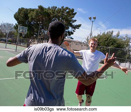 Stock Photograph - Two male friends congratulating each other after basketball game. Fotosearch