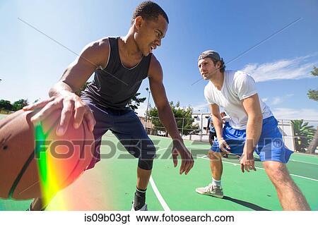 Two male friends playing basketball on outdoor court View Large Photo Image Stock Photograph - Two male friends playing basketball on outdoor court. Fotosearch