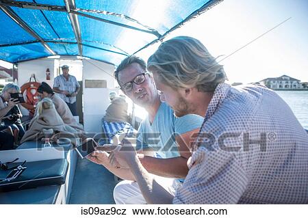 Two male tourists looking at smartphone on boat trip, Cape Town, South Africa View Large Photo Image Stock Photo - Two male tourists looking at smartphone on boat trip, Cape Town, South Africa. Fotosearch