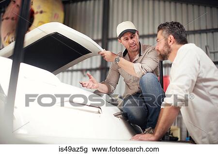 Two men checking boat bodywork in repair workshop View Large Photo Image Stock Image - Two men checking boat bodywork in repair workshop. Fotosearch