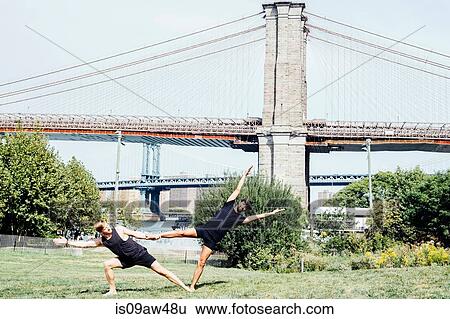 Two men leaning sideways in yoga foot hold position in front of Brooklyn Bridge, New York, USA View Large Photo Image Stock Photograph - Two men leaning sideways in yoga foot hold position in front of Brooklyn Bridge, New York, USA. Fotosearch