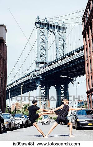 Two men leaning sideways in yoga position in front of Manhattan Bridge, New York, USA View Large Photo Image Stock Photograph - Two men leaning sideways in yoga position in front of Manhattan Bridge, New York, USA. Fotosearch