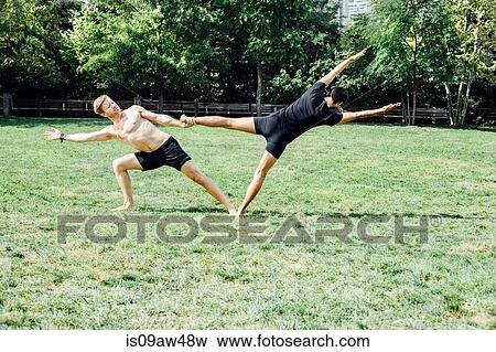 Two men practising yoga foot hold position in park View Large Photo Image Stock Photo - Two men practising yoga foot hold position in park. Fotosearch
