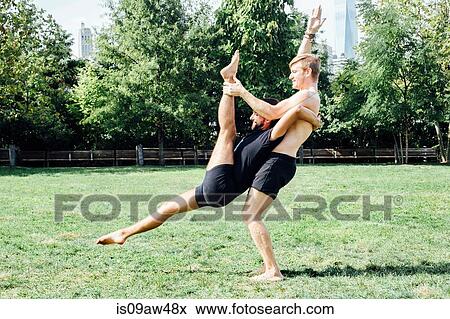Stock Photo - Two men practising yoga lift position in park. Fotosearch