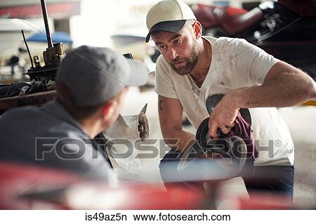 Two men repairing propeller in boat repair workshop View Large Photo Image Picture - Two men repairing propeller in boat repair workshop. Fotosearch
