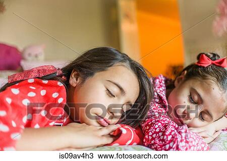 Stock Image - Two sisters sleeping on bed. Fotosearch