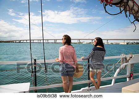 Two women standing on deck of sailing boat, looking at view, rear view View Large Photo Image Stock Photo - Two women standing on deck of sailing boat, looking at view, rear view. Fotosearch