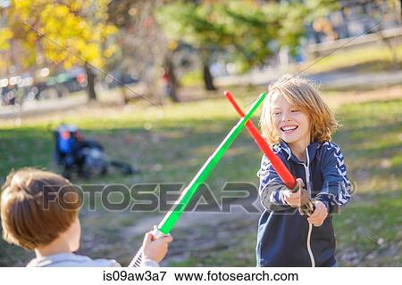 Stock Photo - Two young brothers, play fighting with laser swords. Fotosearch