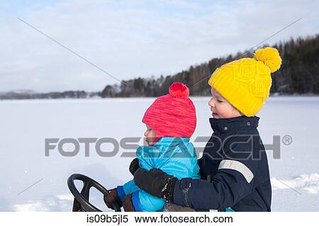 Two young brothers sitting on sledge, in snow covered landscape View Large Photo Image Stock Photography - Two young brothers sitting on sledge, in snow covered landscape. Fotosearch