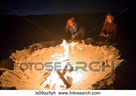 Stock Image - Two young girls cooking food on campfire. Fotosearch