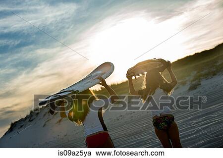 Two young girls in sea, holding surfboards, rear view View Large Photo Image Stock Image - Two young girls in sea, holding surfboards, rear view. Fotosearch