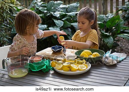 Two young sisters preparing lemon juice for lemonade at garden table View Large Photo Image Stock Image - Two young sisters preparing lemon juice for lemonade at garden table. Fotosearch