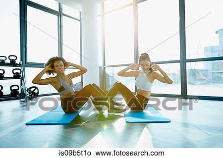 Two young women exercising in gym, doing sit-ups View Large Photo Image Picture - Two young women exercising in gym, doing sit-ups. Fotosearch